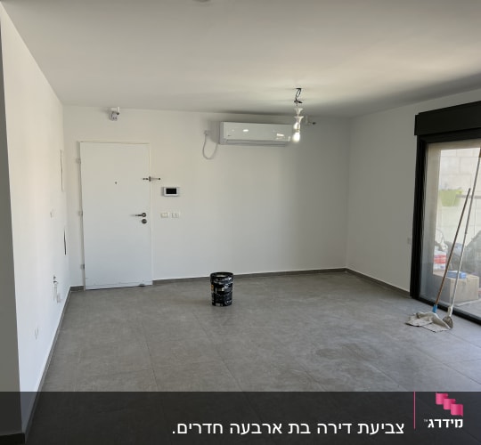 דלי צבע שחור ומברשות על רצפה בחדר ריק